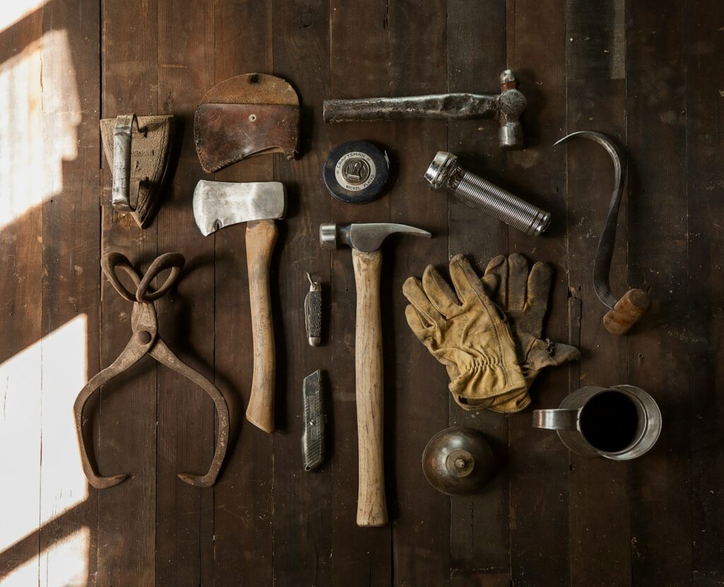 clothes iron, hammer, axe, flashlight and pitcher on brown wooden table - resources